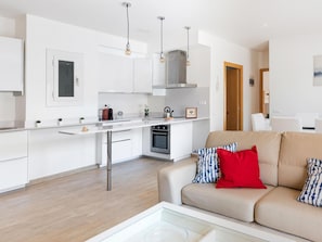 A modern kitchen with white cabinets, a stainless steel range hood, and a built-in oven.