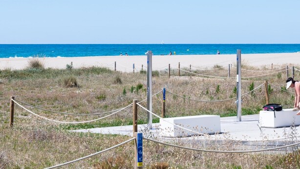 A beach with a rope barrier, a white structure, and a clear blue sky.