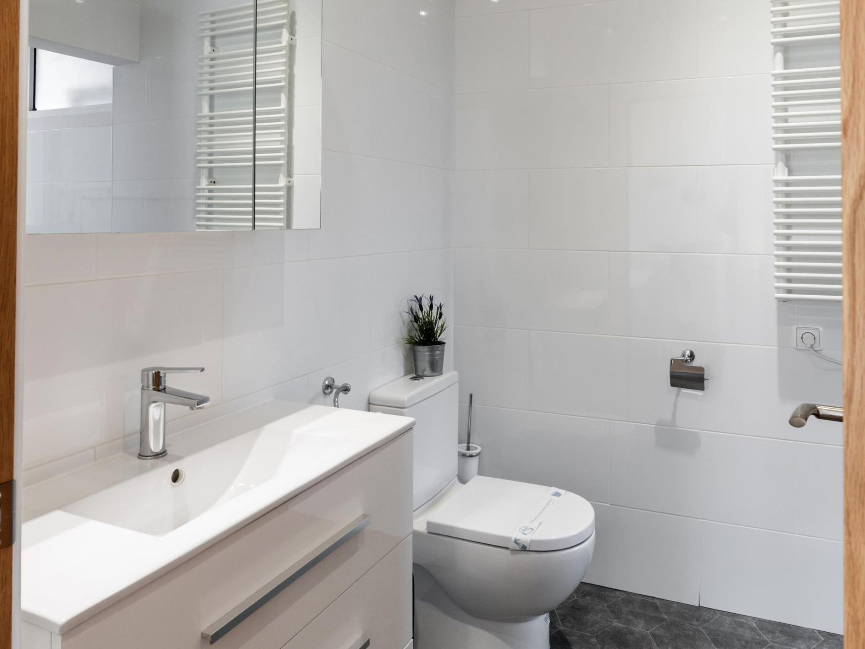 Un baño moderno con lavamanos, inodoro y tocador blancos.