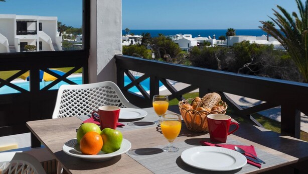 A table set for breakfast with fruits, juice, and bread, overlooking a coastal view. - Apt 30 El Golfo (Haria)