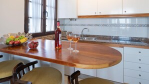 A kitchen with a wooden countertop, white cabinets, a sink, and a window with curtains. - Apt 30 El Golfo (Haria)