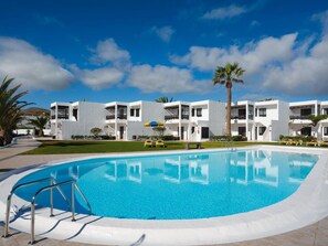 A modern hotel with a swimming pool, multiple balconies, and palm trees. - Apt 30 El Golfo (Haria)