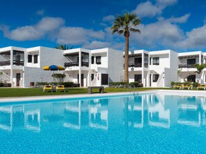 A modern hotel with a pool, multiple balconies, and a clear blue sky. - Apt 30 El Golfo (Haria)