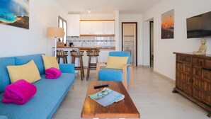 A living room with a blue sofa, a coffee table, and a TV. - Apt 30 El Golfo (Haria)
