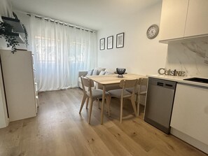 Een moderne keuken met een eettafel, stoelen, een vaatwasser en een koelkast.