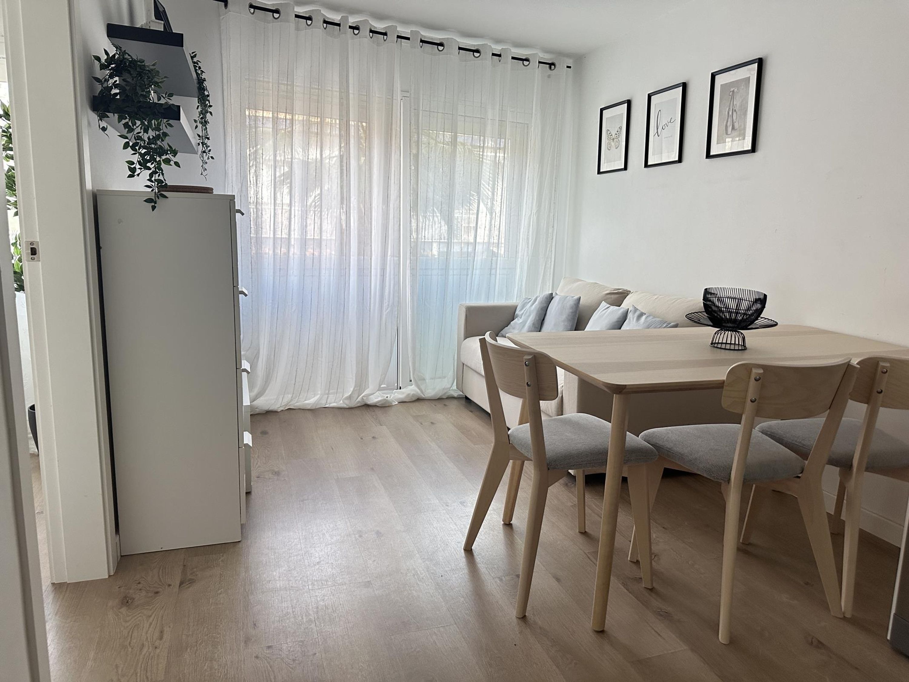 A modern, minimalist living space with a dining area, a sofa, and a refrigerator.