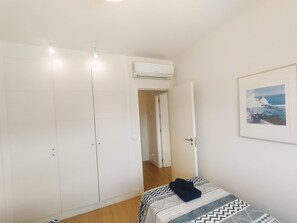Ein Schlafzimmer mit Bett, Kleiderschrank, Klimaanlage und einem gerahmten Bild an der Wand.