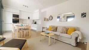 En moderne lejlighed med et spiseområde, en sofa med mønstrede puder og et lille bord med en skål.