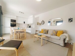 Ein modernes Apartment mit Essbereich, einer Couch mit gemusterten Kissen und einem kleinen Tisch mit einer Schüssel.