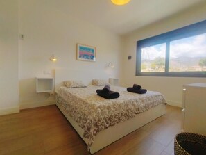 Ein Schlafzimmer mit einem großen Bett, zwei Nachttischen, einem Fenster mit Aussicht und einem Gemälde an der Wand.