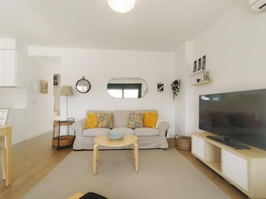A living room with a sofa, TV, and a small table.