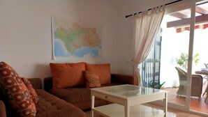 Un salon avec un canapé marron, une table basse en verre et une carte accrochée au mur.