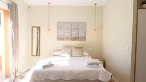 Een slaapkamer met een groot bed, nachtkastjes, een spiegel en een kunstwerk aan de muur.