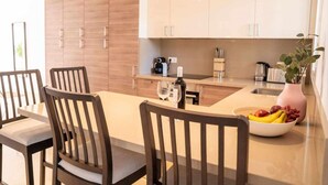 Una cocina moderna con armarios de madera, una isla central y un comedor con sillas.