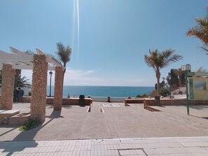 A paved walkway leading to a beach with stone pillars and a clear view of the sea. - Apartamento Bah a Nerja Sun (Nerja)