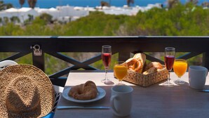 A breakfast setup with croissants, orange juice, and wine glasses on a table overlooking a scenic ocean view. - Apt 26 Timanfaya (Haria)