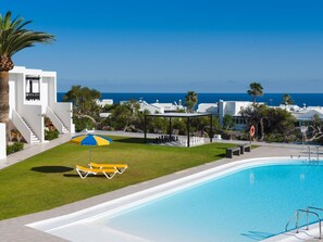 A pool area with a clear view of the ocean, a white building with a staircase, and a gazebo. - Apt 32 Las Malvas (Haria)