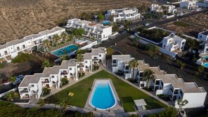 Un complexe hôtelier comprenant plusieurs bâtiments blancs, une piscine centrale et de nombreux espaces verts.