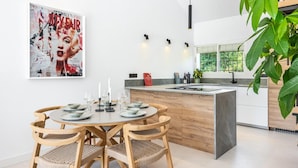 A modern kitchen with a central island, wooden chairs, and a dining table set for four. - Agrupadas Beautiful Duplex With Amazing Location (Marbella)