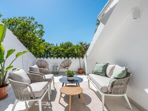 An outdoor patio with wicker furniture, a round table, and a potted plant. - Agrupadas Beautiful Duplex With Amazing Location (Marbella)