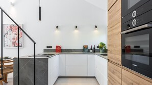 A modern kitchen with white cabinets, a black countertop, and a Bosch oven. - Agrupadas Beautiful Duplex With Amazing Location (Marbella)