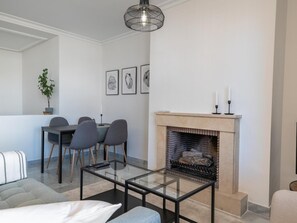 A modern living room with a glass coffee table, a fireplace, a dining area with chairs, and a hanging light fixture. - Se or o de Aloha 2 Bedroom (Marbella)