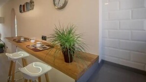 A modern kitchen with a wooden countertop, a potted plant, and a wall clock. - Beachfront Sunny Apartment Sea Mountain View (Castelldefels)