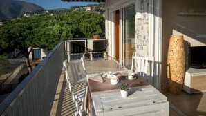 A balcony with a table, chairs, a potted plant, and a decorative vase. - Beachfront Sunny Apartment Sea Mountain View (Castelldefels)