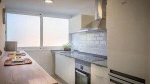 A modern kitchen with a wooden countertop, a built-in oven, and a stainless steel range hood. - Beachfront Sunny Apartment Sea Mountain View (Castelldefels)