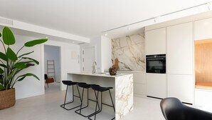 A modern kitchen with a marble backsplash, a central island with bar stools, and a built-in oven.