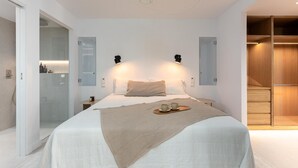 A modern bedroom with a large bed, bedside lamps, a ceiling fan, and a walk-in closet.