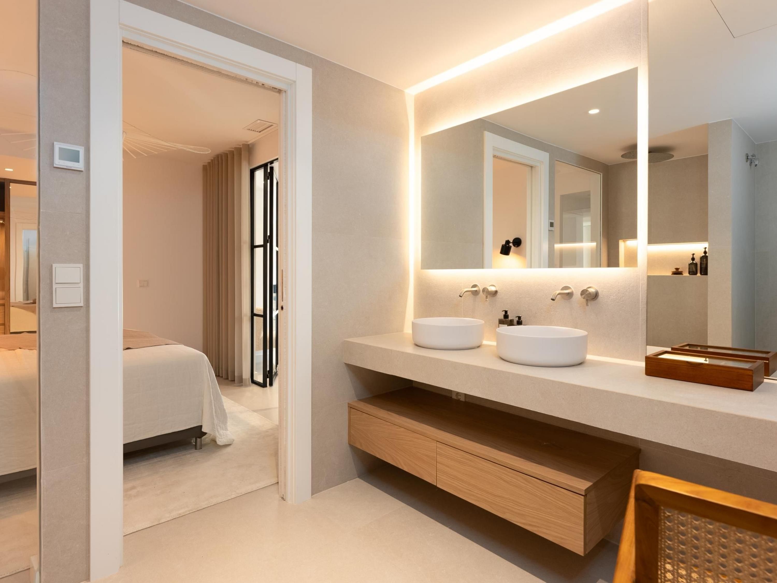 A modern bathroom with two sinks, a large mirror, and a wooden vanity.