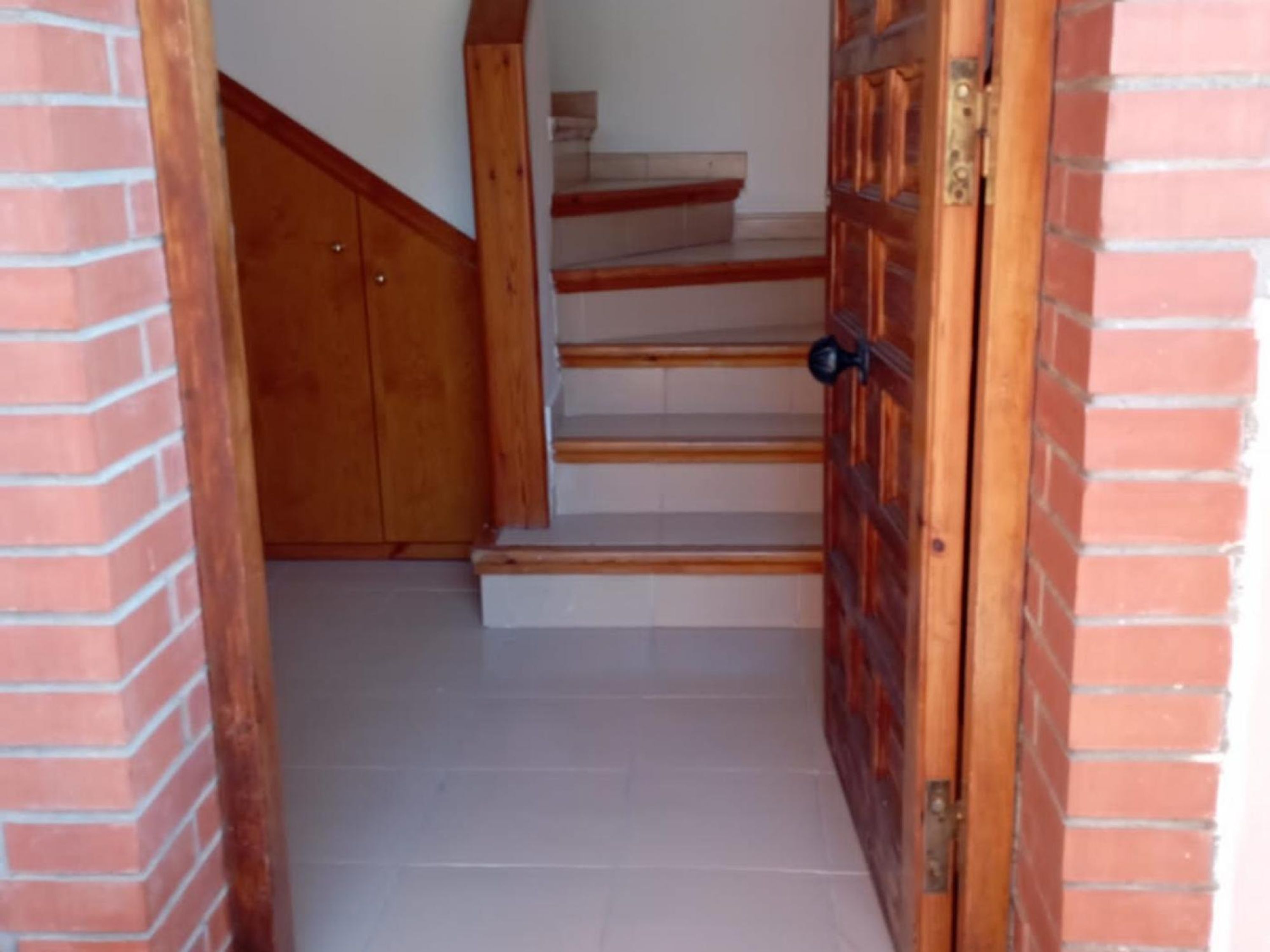 A staircase with wooden steps and a wooden door with a black handle.
