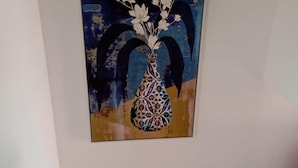 Un dipinto raffigura un vaso con fiori appeso a una parete.