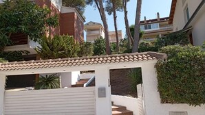 Un edificio residenziale con facciata bianca, tetto in tegole e ingresso con cancello.