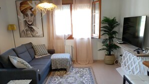Un soggiorno con divano, tappeto decorato, televisore e pianta in vaso.