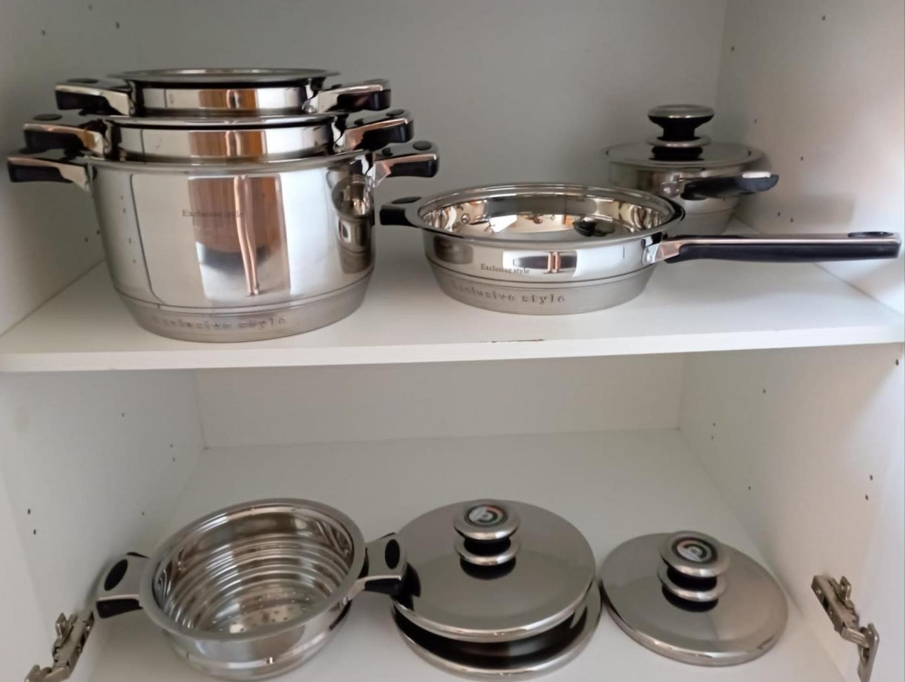 A kitchen shelf with stainless steel cookware, including pots and pans.