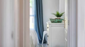 Un pasillo con un armario blanco, una planta pequeña y una cortina azul.