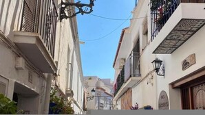 A narrow street with white buildings, balconies, and hanging street lamps. - Nerja Sun Apartamento Jabega Torrecilla (Nerja)