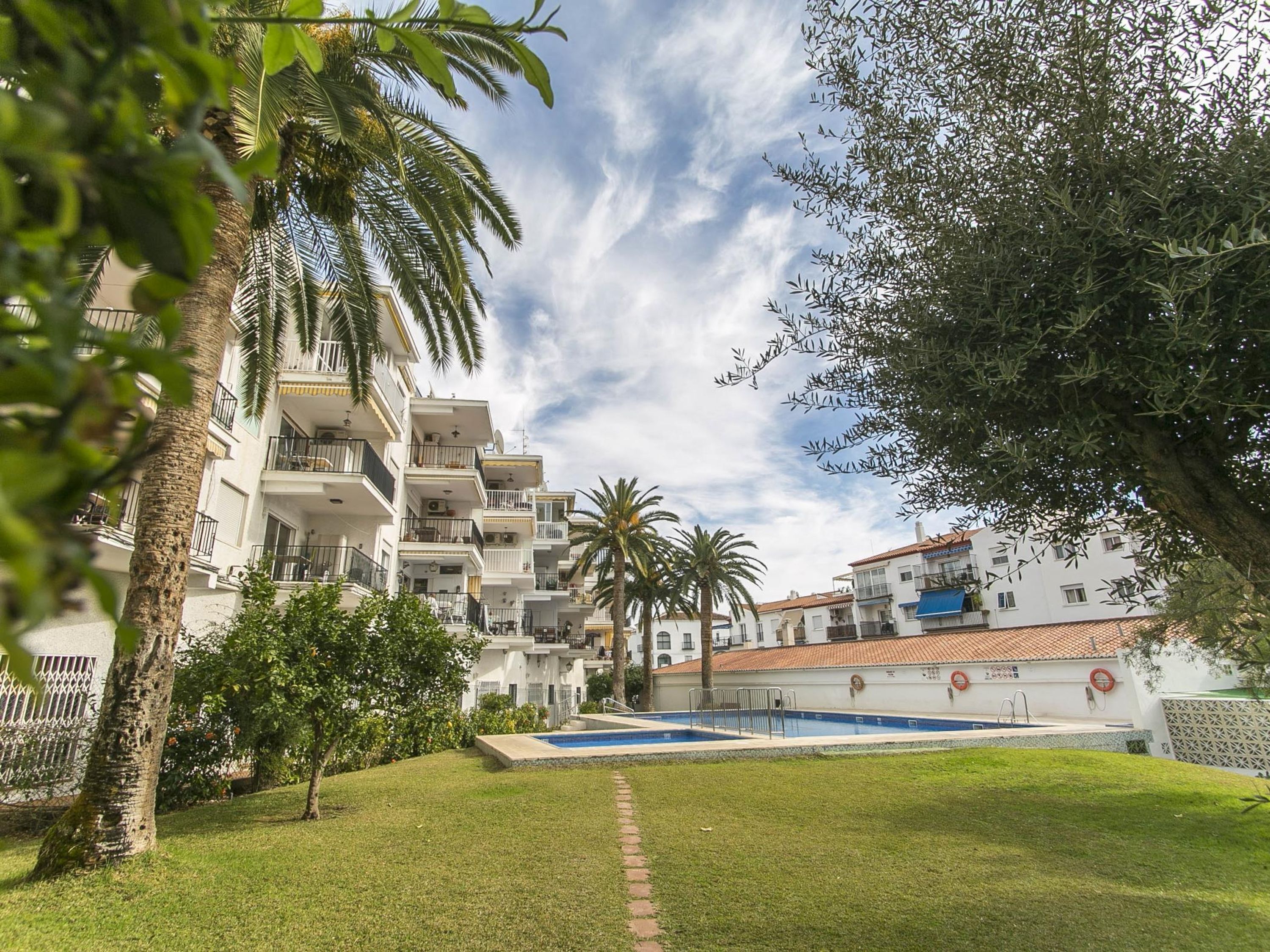 Un immeuble résidentiel doté de nombreux balcons, d’une piscine et entouré de verdure.
