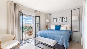 Une chambre moderne avec un grand lit, un banc, une chaise et un balcon avec vue.