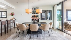 Un espace de salle à manger moderne avec une table ronde, six chaises et des luminaires suspendus.