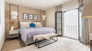 Une chambre moderne avec un lit, des tables de chevet, un banc et une grande fenêtre donnant sur un beau paysage.