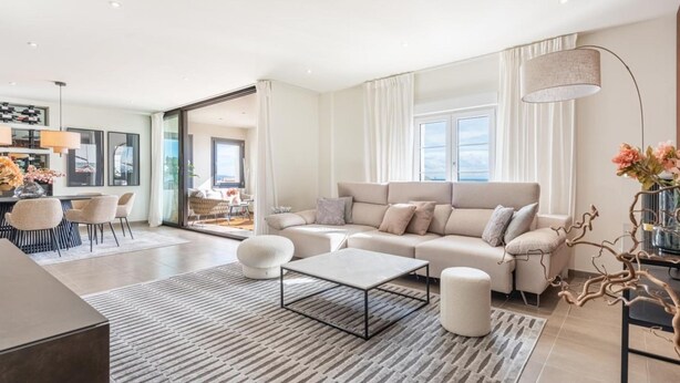 Un salon moderne comprenant un canapé, une table basse et un coin repas avec des chaises.