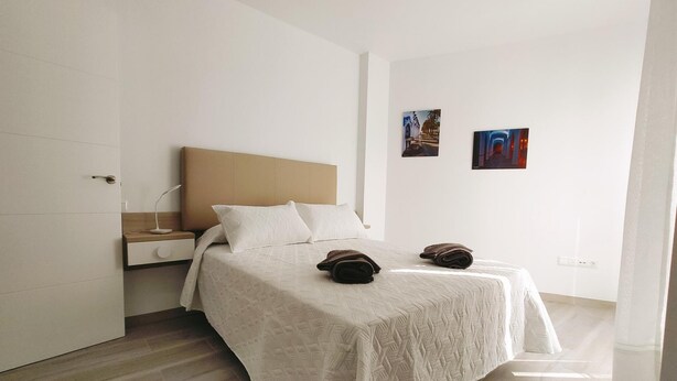 A modern bedroom with a bed, a nightstand, and a wall-mounted lamp. - Apartamento Bronce A Centro Nerja Sun (Nerja)