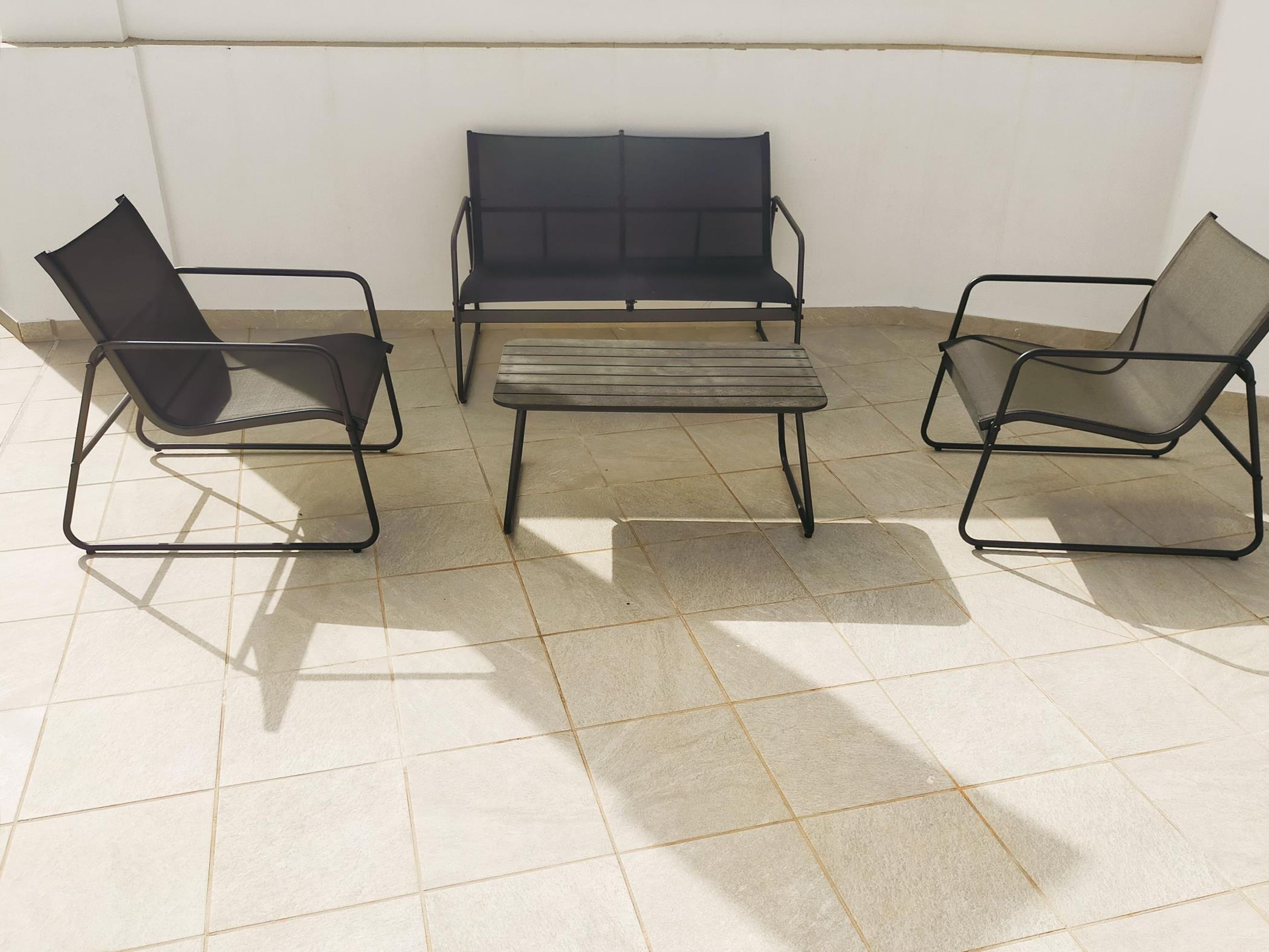 A room with a bench and two chairs with metal frames.