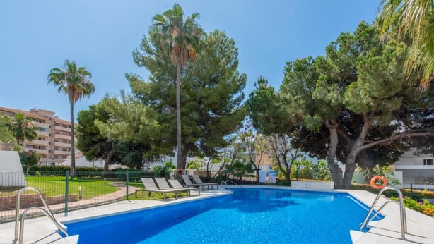 A rectangular swimming pool with clear blue water, surrounded by a tiled deck. There are lounge chairs and a lifebuoy on the deck. - Sol y Paz 3 Family Apartment With Great Location (Marbella)