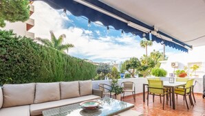 A covered outdoor patio with a sofa, chairs, and a table. - Sol y Paz 3 Family Apartment With Great Location (Marbella)