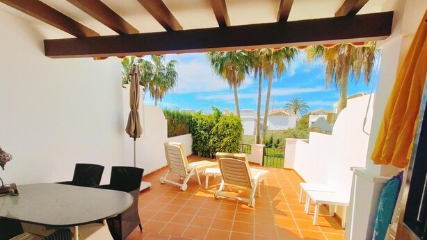 A patio with a table and chairs, a pergola, and a view of palm trees and the sea. - Casa Cipreses 5 Nerja Sun (Nerja)