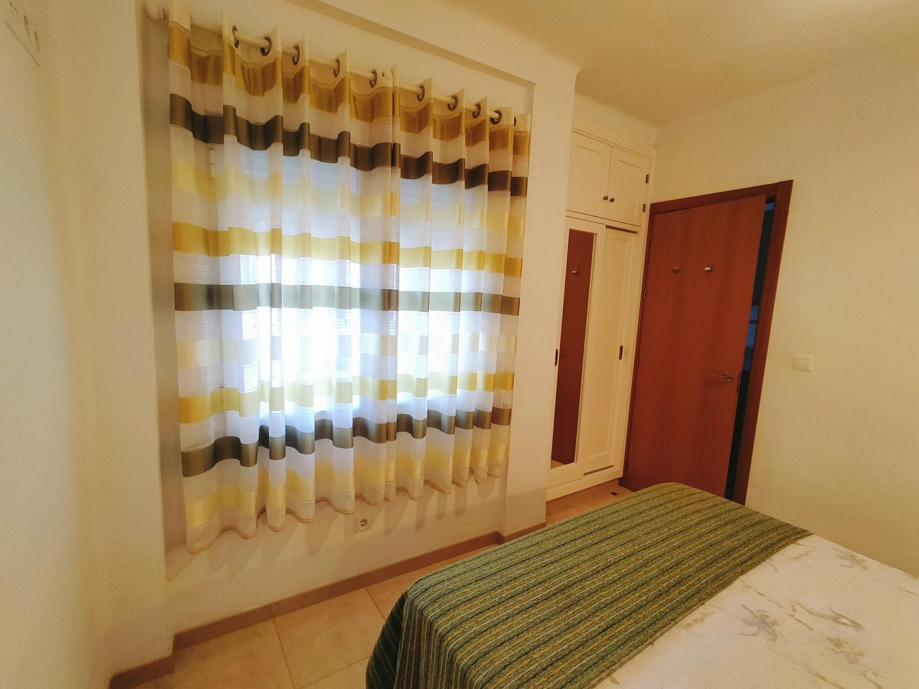 A bedroom with a bed, a wooden door, and a wardrobe.